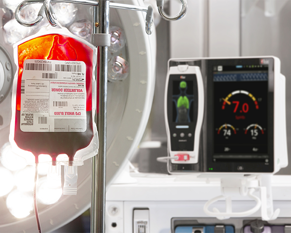 IV blood bag handing near bedside monitoring device.