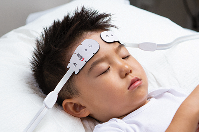 Child sleeping in bed wearing Masimo O3 Sensors.